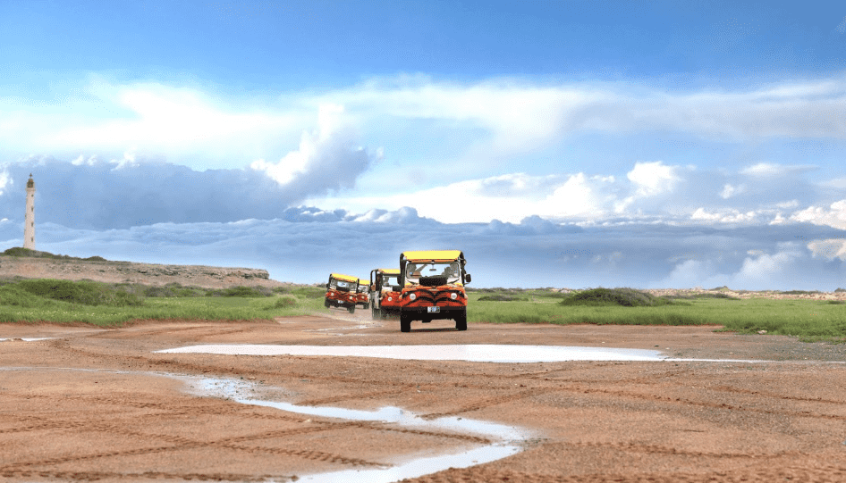 line of off-road jeeps with lighthouse in the background